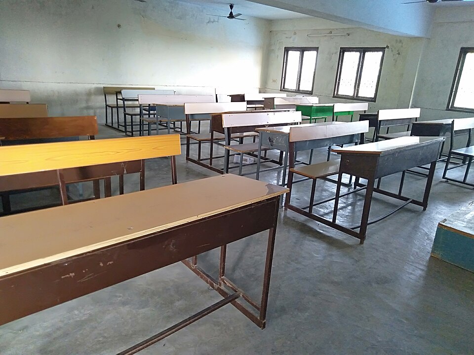 Aula vacía con mesas y sillas.