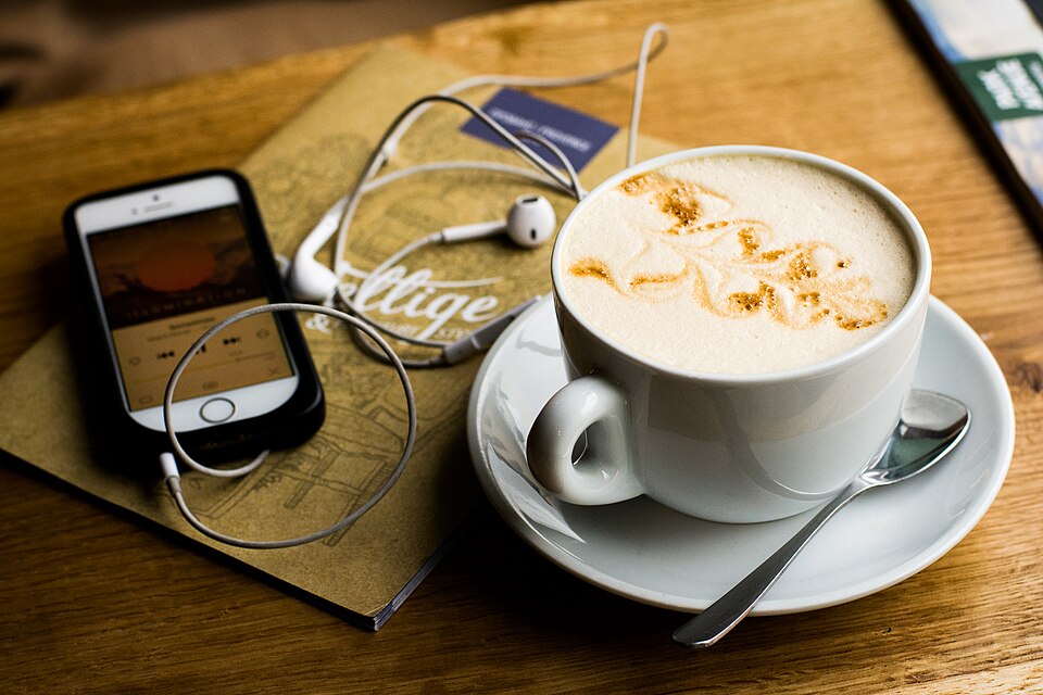 Taza de café junto a un teléfono sobre una mesa.