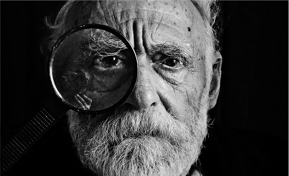 Retrato en blanco y negro de un hombre con una lupa.