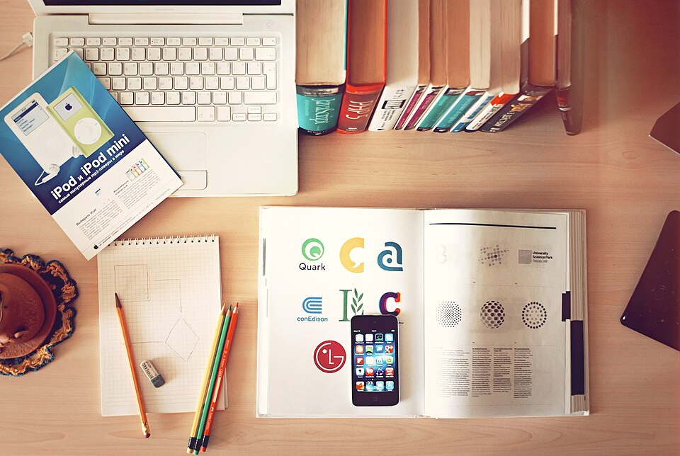 Libros, lápices, un portátil y un teléfono sobre un escritorio.
