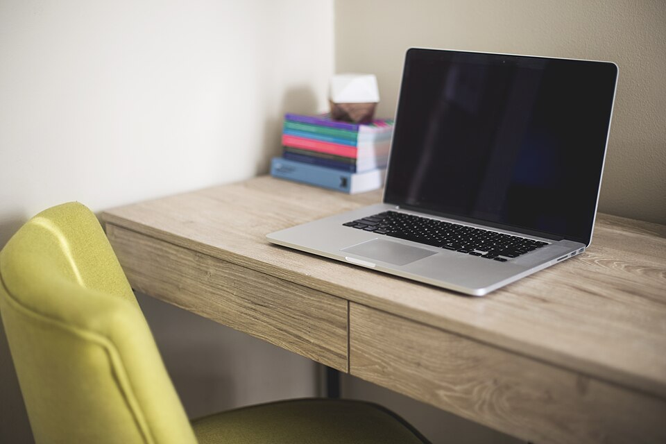 Portátil y libros sobre una superficie de trabajo.